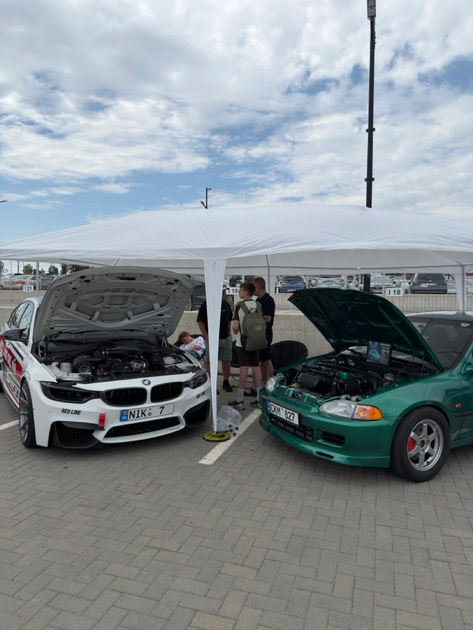 BMW M3 a lui Nikita și o Honda Civic cu capotele deschise sub un cort, la un eveniment auto