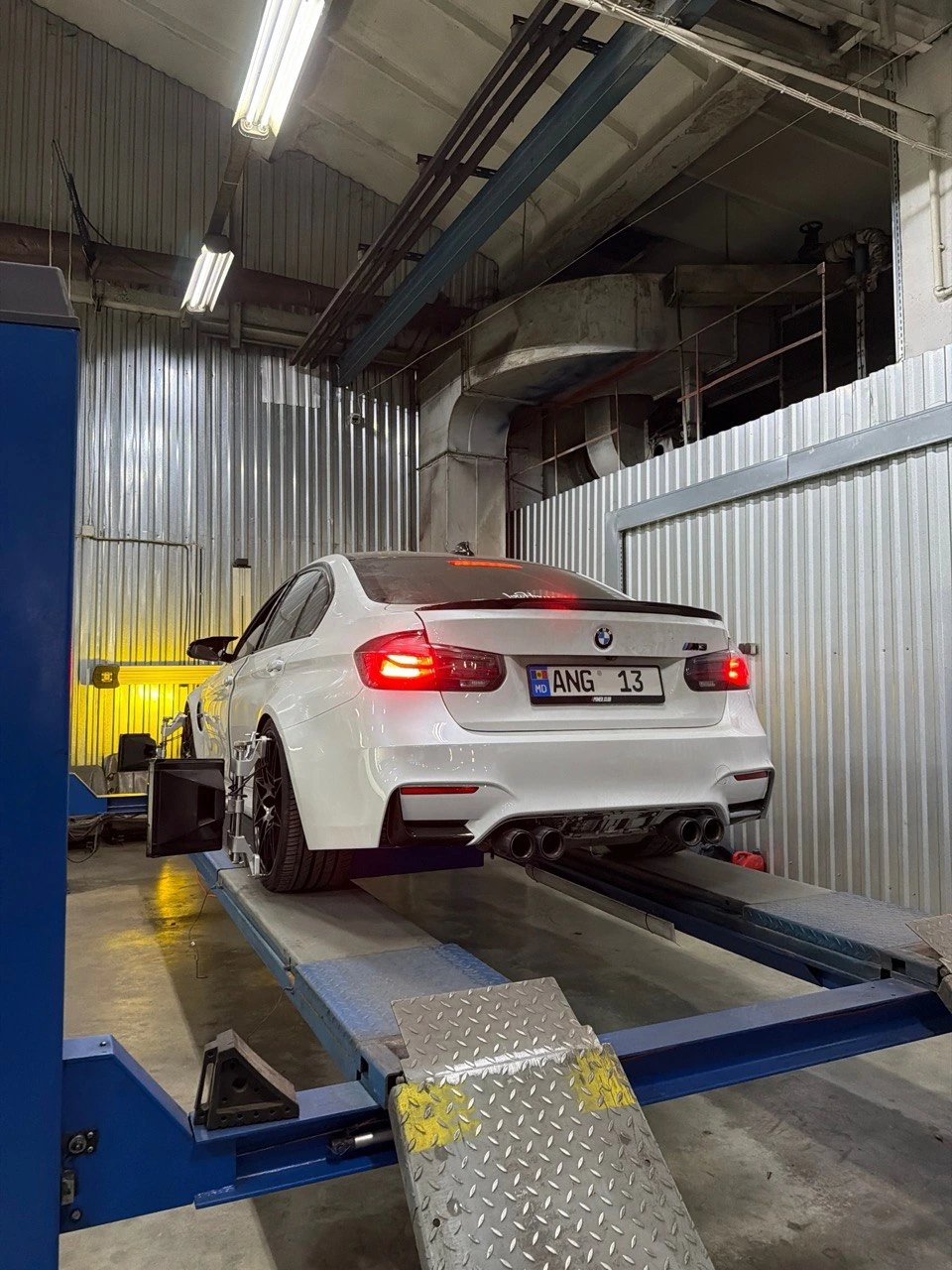 BMW M3 albă pe standul de geometrie a roților
