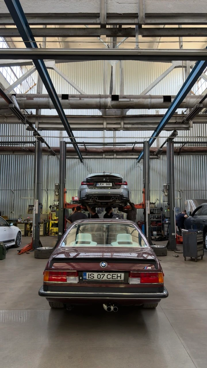 BMW Seria 6 E24 clasică și BMW M3 G80 pe elevator în atelier