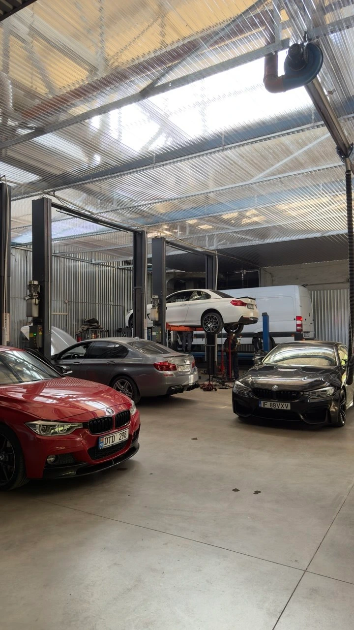 Vedere de ansamblu a atelierului: mai multe BMW, unul pe elevator